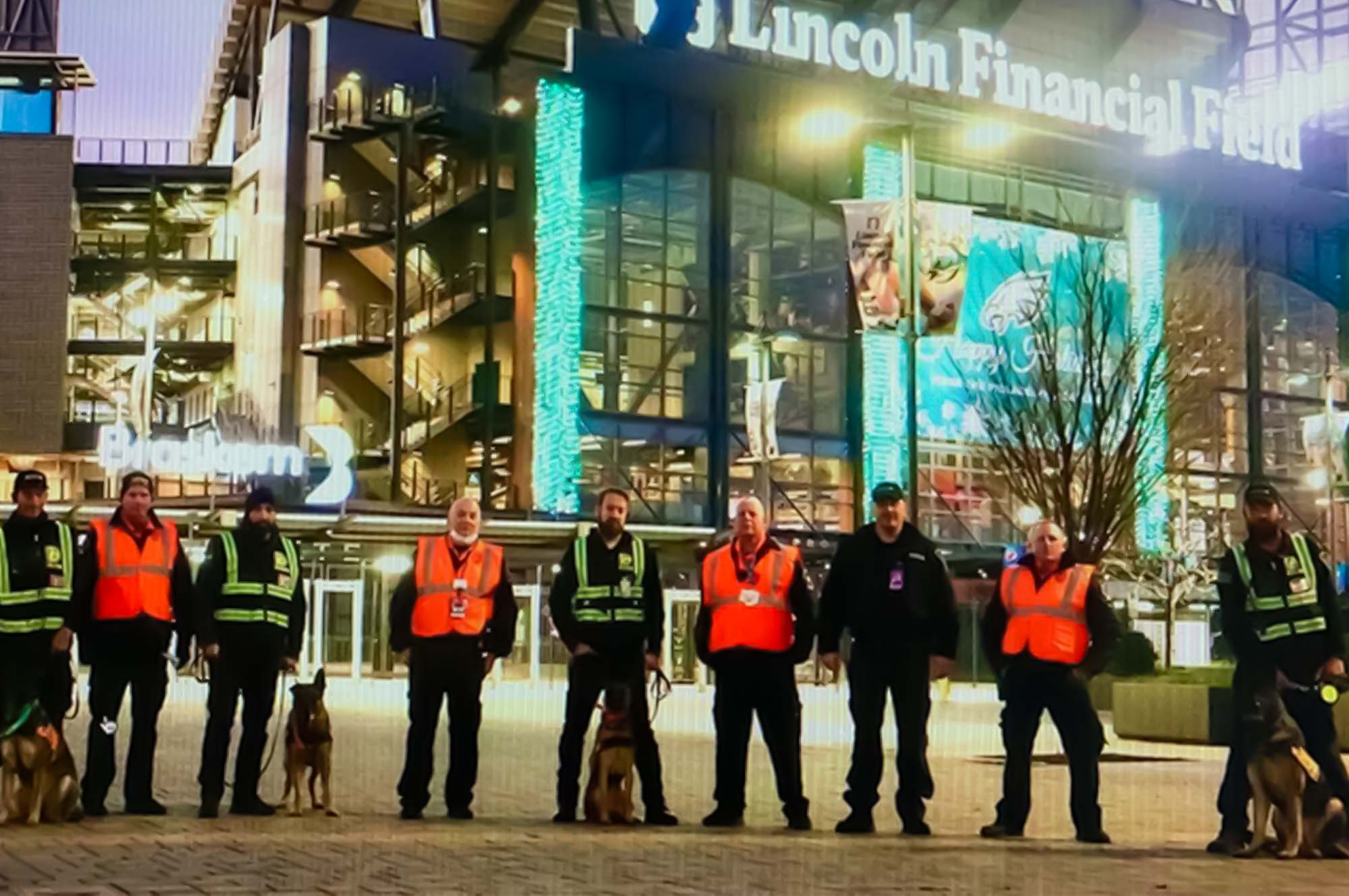 a group of men with dogs standing in front of lincoln financial field