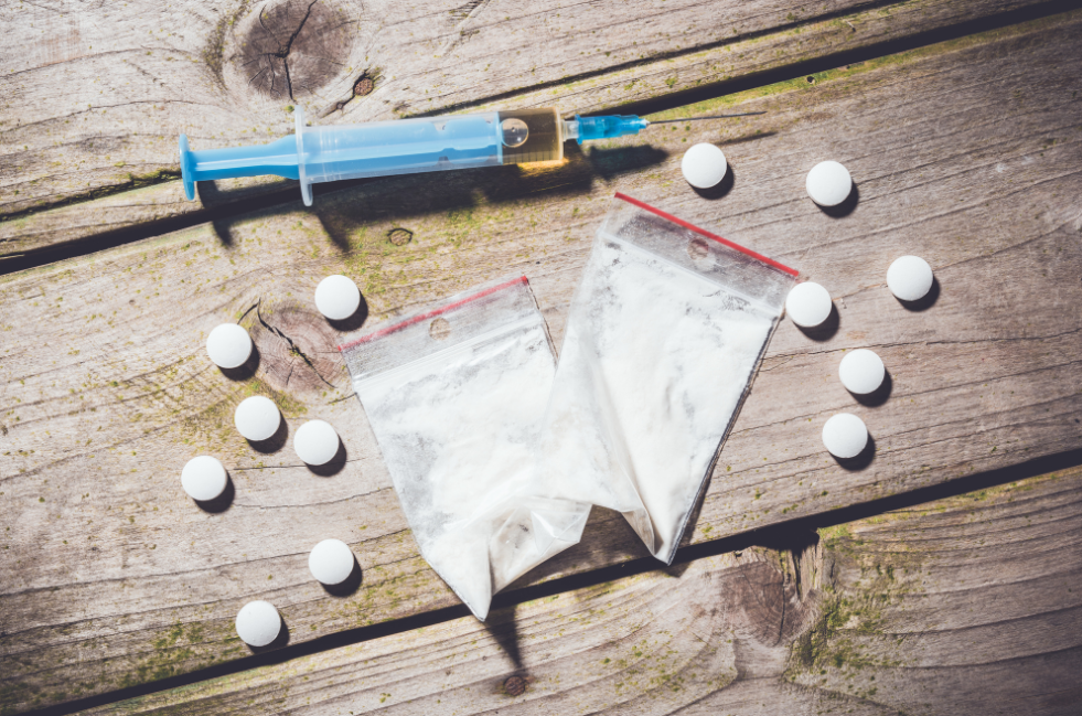 a syringe, white pills, and white powder in two bags