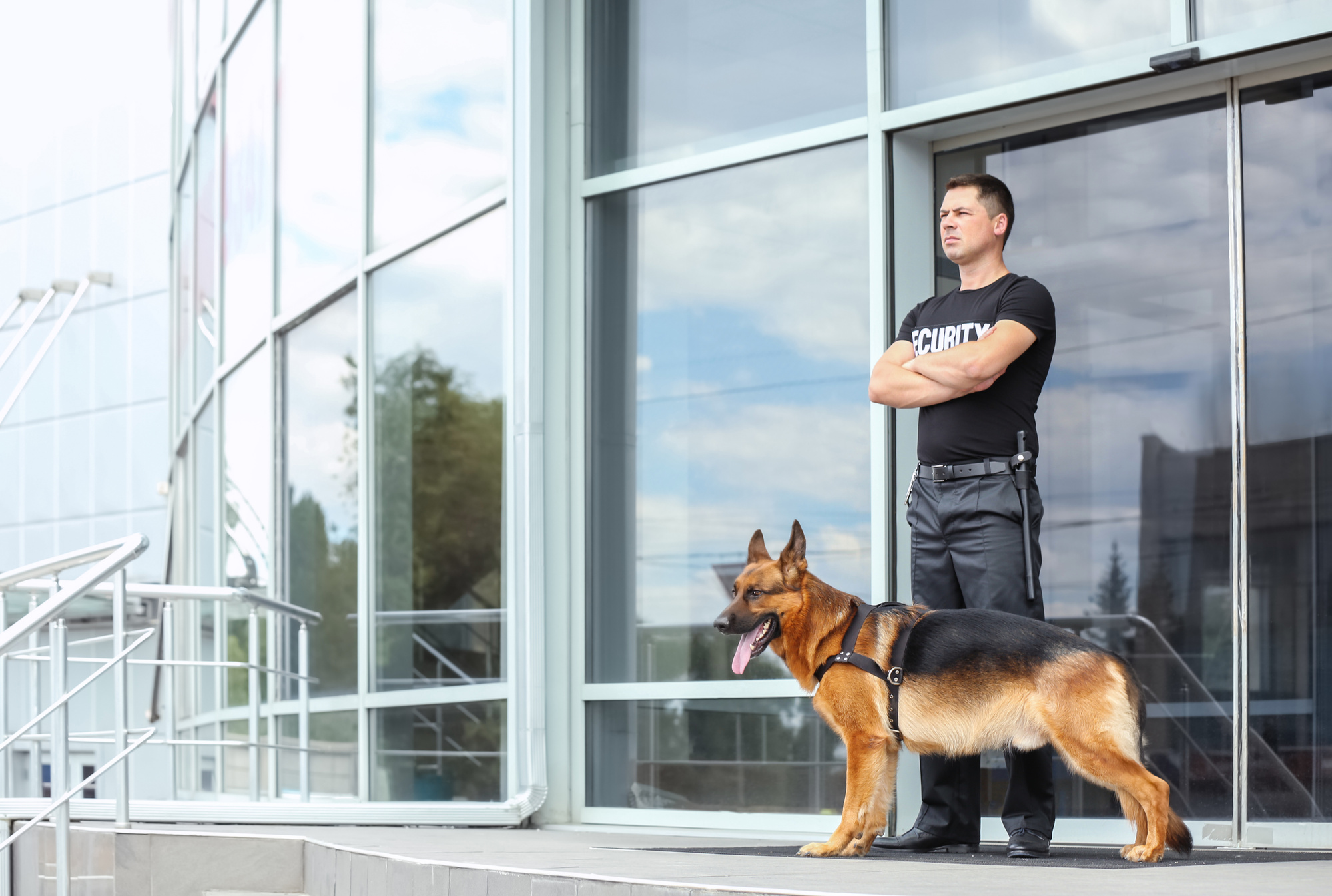 a security guard with his dog standing in front of a building
