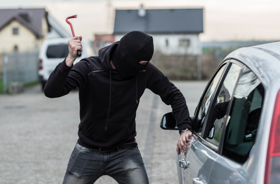 a man in a mask trying to break into a car