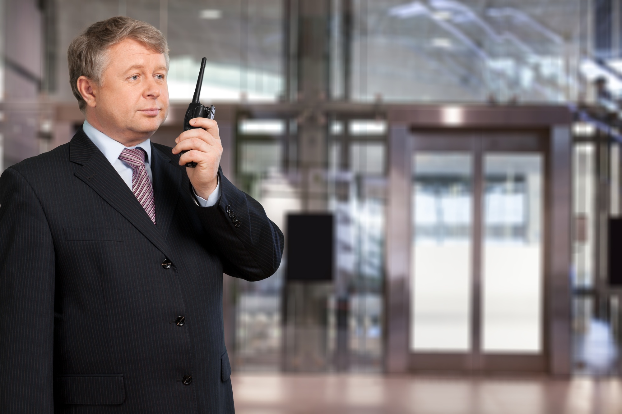 a man in a suit and tie talking on a walkie talkie